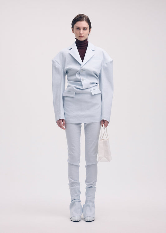 A model wears the Issey Miyake LIKE TORSO LIKE BLAZER trousers.