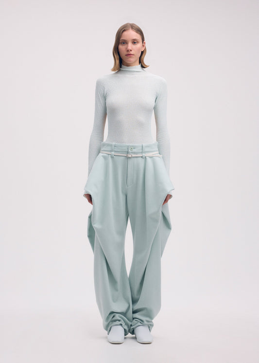 A model wears the Issey Miyake WOOL TWEED PANTS trousers.