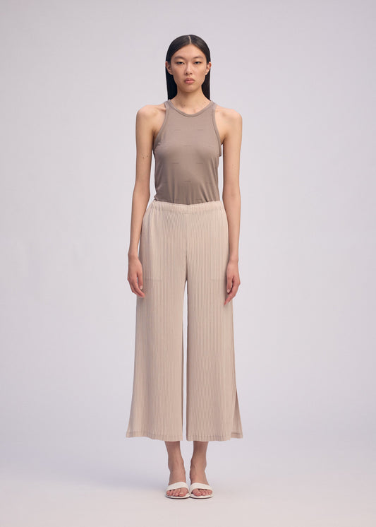 A model wears the Issey Miyake HATCHING BOTTOMS pants.