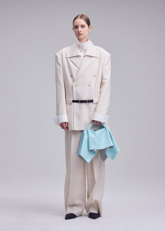 A model wears the ISSEY MIYAKE SQUARE BAG(LEATHER) bag.