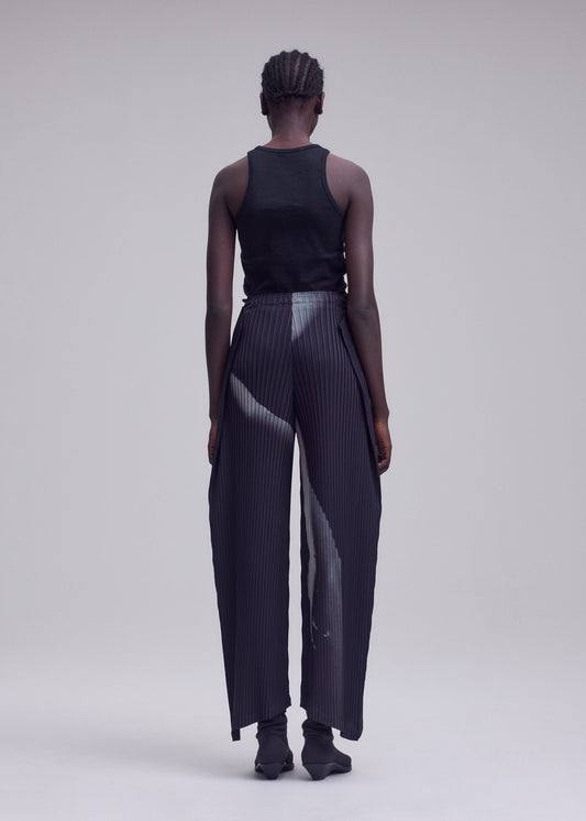 A model wears the ISSEY MIYAKE HANDS OF LOVER PLEATS trousers.