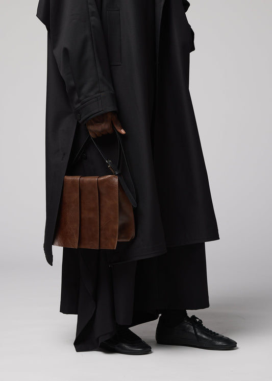 A model wears the IM MEN LEATHER PLEATS bag.