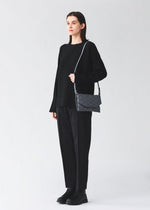 A model wears the BAO BAO ISSEY MIYAKE TONNEAU MATTE tonneau-matte-shoulder-bag-dark-grey.