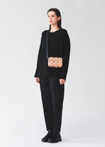 A model wears the BAO BAO ISSEY MIYAKE CUBOID cuboid-shoulder-bagsmall-off-white.