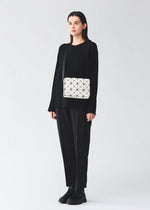 A model wears the BAO BAO ISSEY MIYAKE CUBOID cuboid-shoulder-baglarge-matte-black.