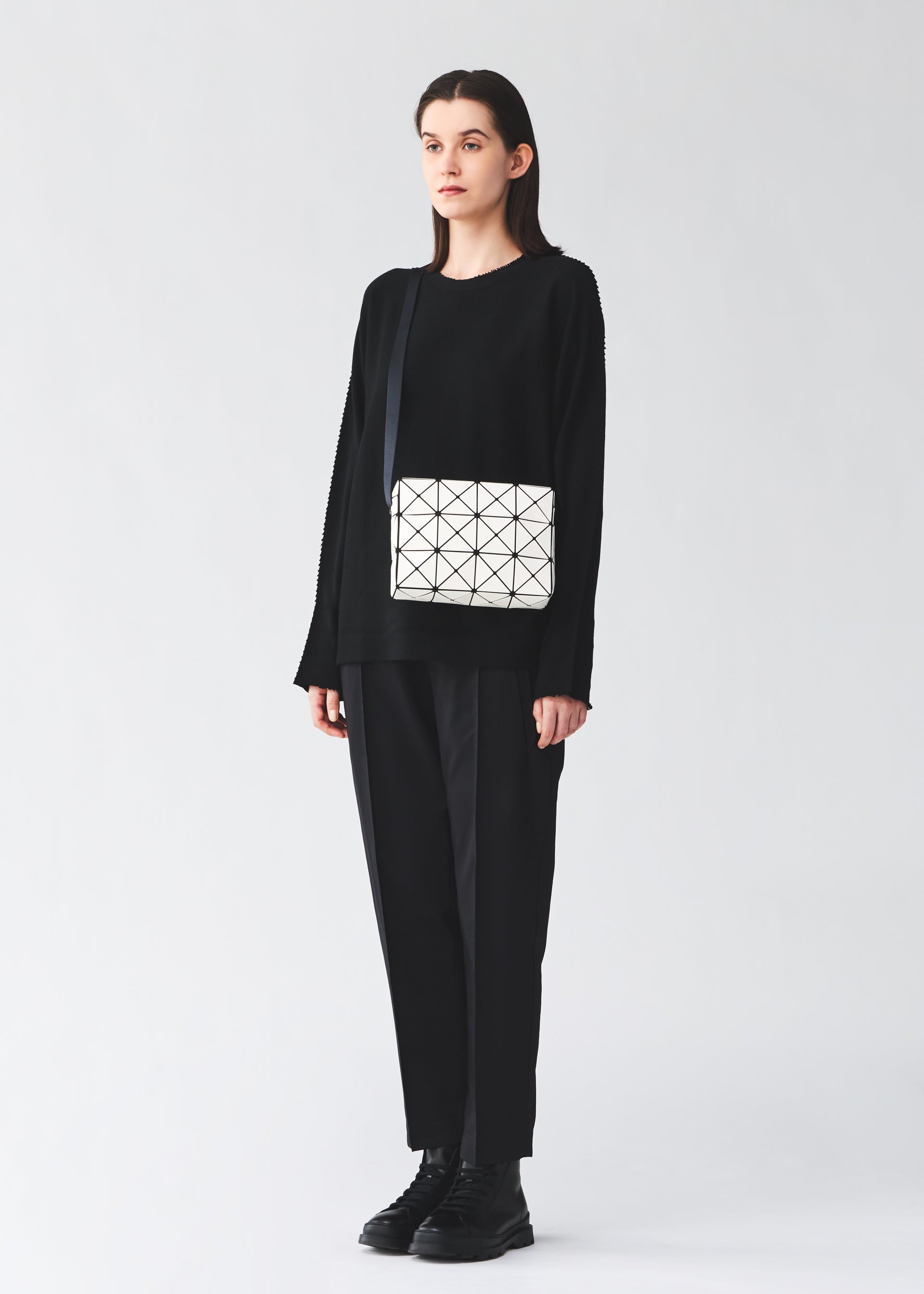 A model wears the BAO BAO ISSEY MIYAKE CUBOID cuboid-shoulder-baglarge-matte-black.