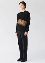 A model wears the BAO BAO ISSEY MIYAKE SADDLE BAG REFLECTOR saddle-bag-reflector-shoulder-bag-copper-brown.