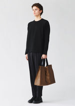 A model wears the BAO BAO ISSEY MIYAKE CART REFLECTOR cart-reflector-tote-bag-copper-brown.