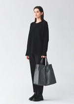 A model wears the BAO BAO ISSEY MIYAKE CART REFLECTOR cart-reflector-tote-bag-1.