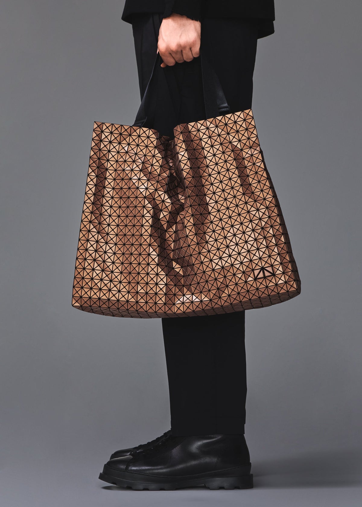 A model wears the BAO BAO ISSEY MIYAKE CART REFLECTOR cart-reflector-tote-bag-1.