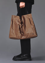 A model wears the BAO BAO ISSEY MIYAKE CART REFLECTOR cart-reflector-tote-bag-1.