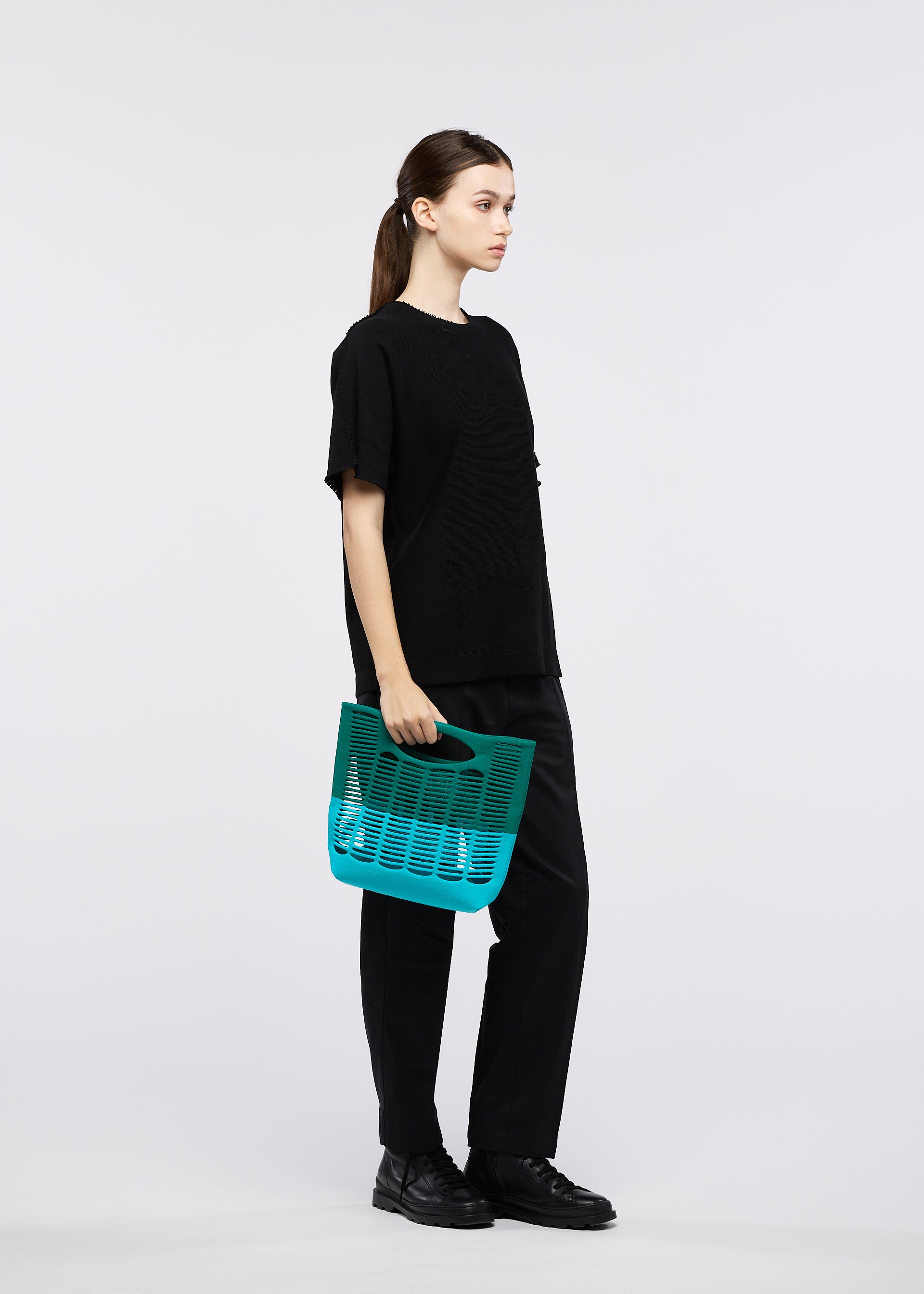 A model wears the GOOD GOODS ISSEY MIYAKE MOKKO BI-COLOR bag.