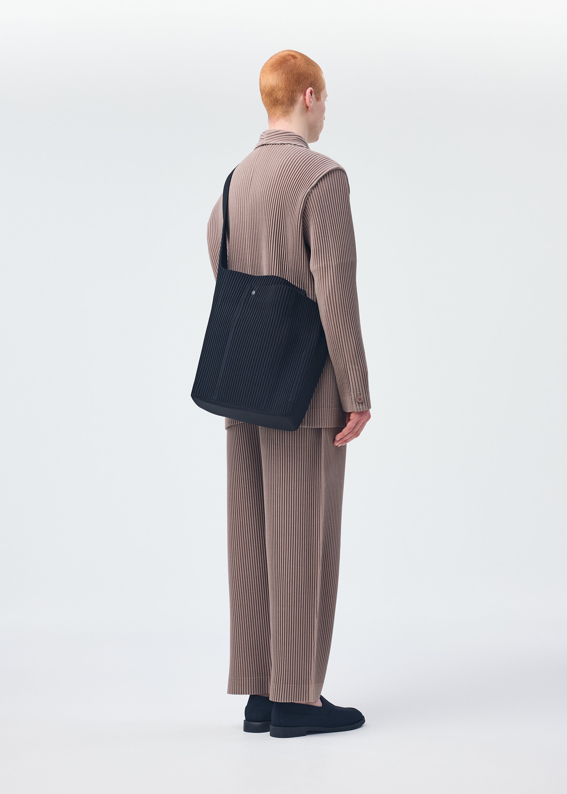 A model wears the Homme Plisse Issey Miyake UTILITY bag.