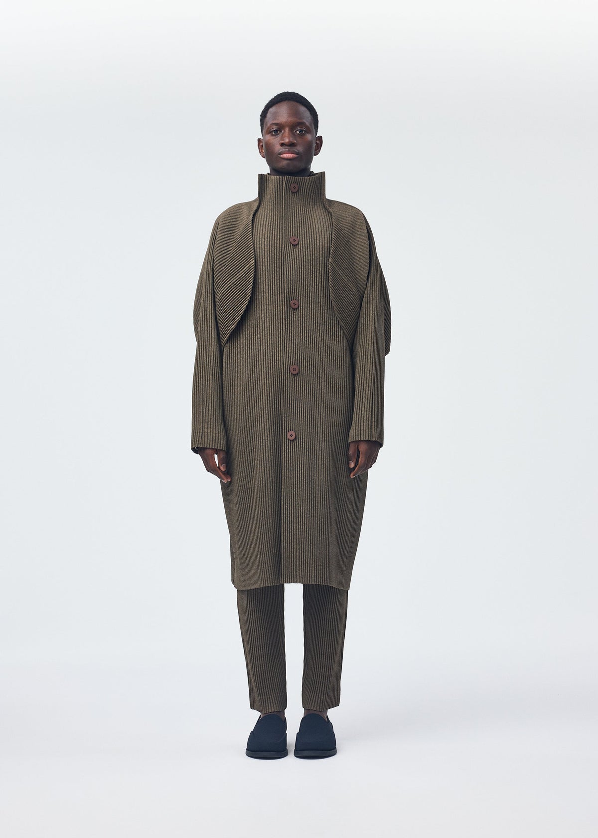 A model wears the Homme Plisse Issey Miyake WOOL LIKE LIGHT coat.