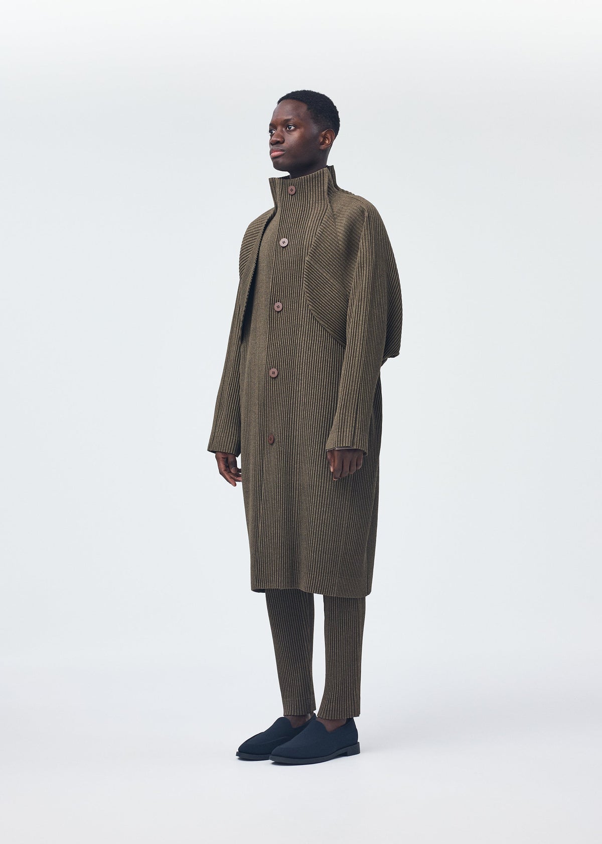 A model wears the Homme Plisse Issey Miyake WOOL LIKE LIGHT coat.