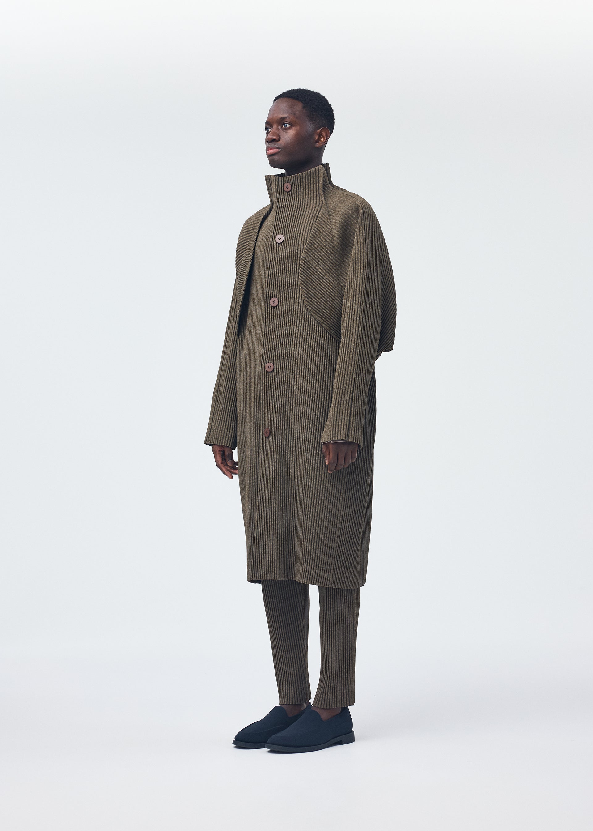 A model wears the Homme Plisse Issey Miyake WOOL LIKE LIGHT coat.