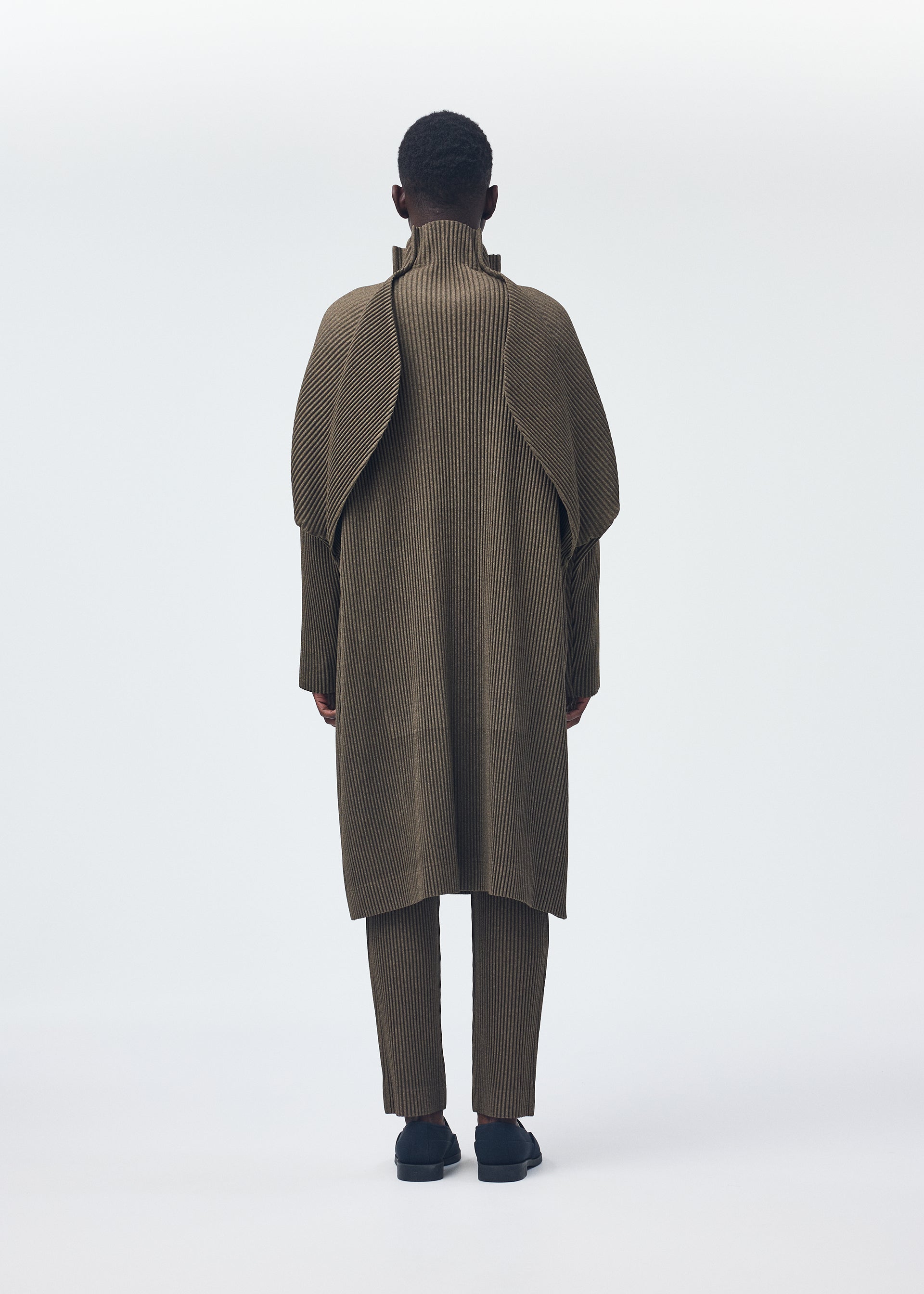 A model wears the Homme Plisse Issey Miyake WOOL LIKE LIGHT coat.