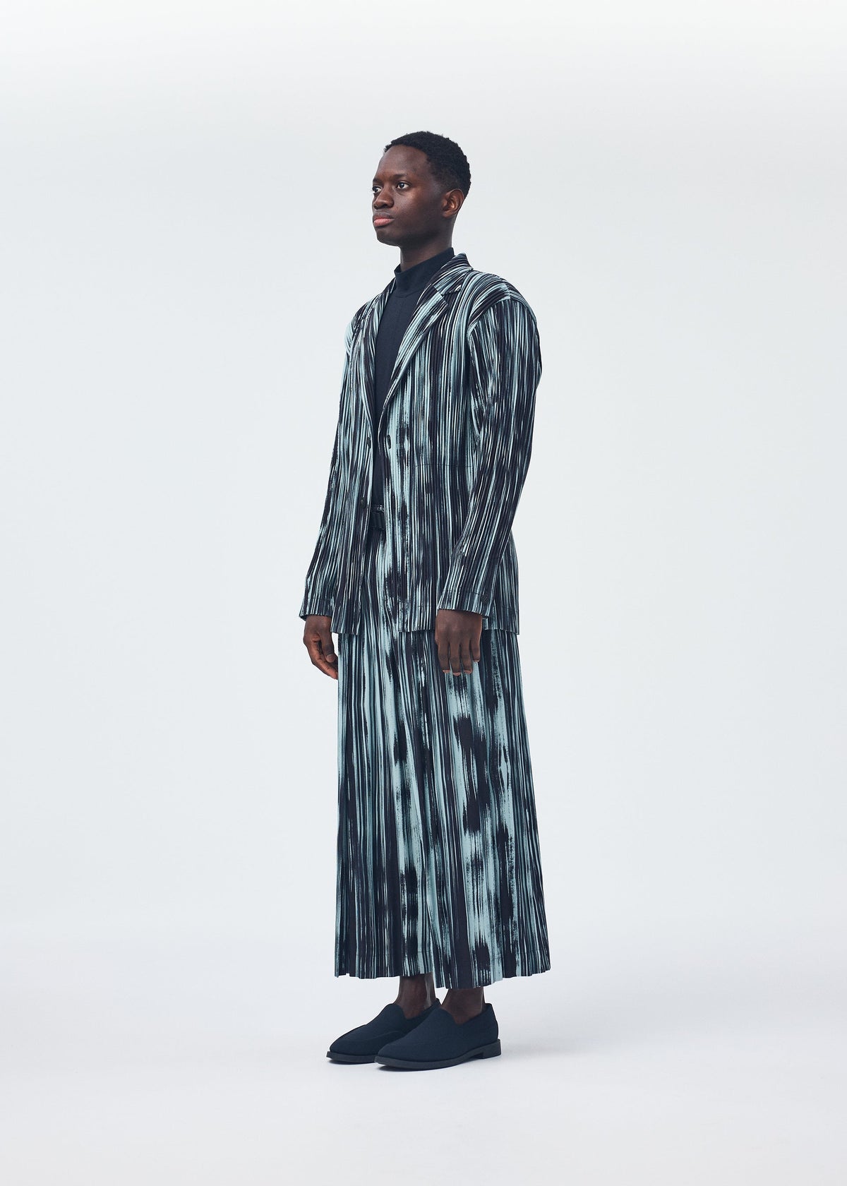 A model wears the HOMME PLISSÉ ISSEY MIYAKE BRUSHSTROKE STRIPE jacket.
