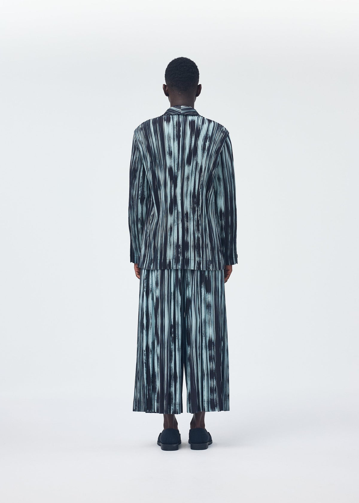 A model wears the HOMME PLISSÉ ISSEY MIYAKE BRUSHSTROKE STRIPE jacket.