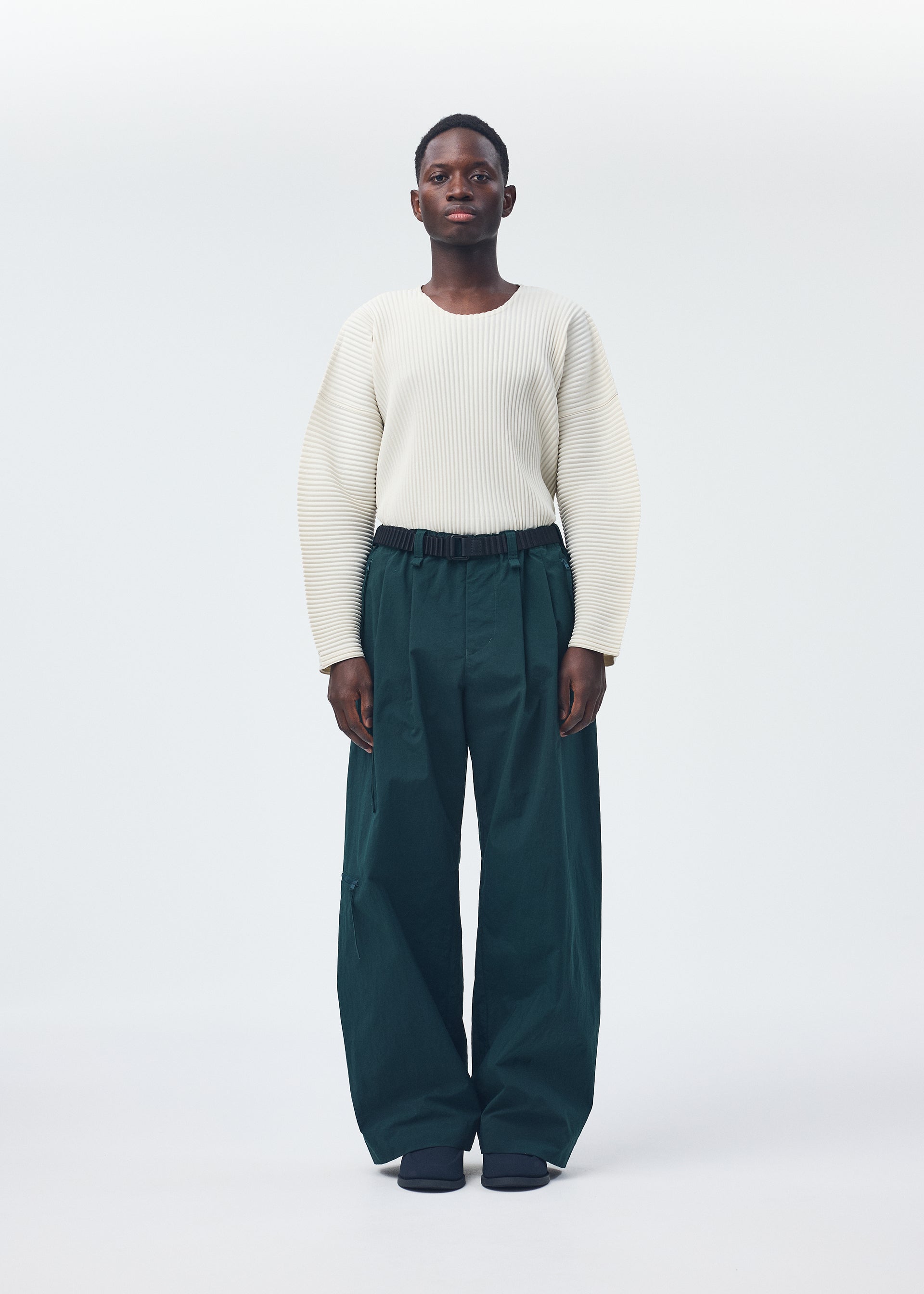 A model wears the Homme Plisse Issey Miyake QUARRY Trousers trousers.