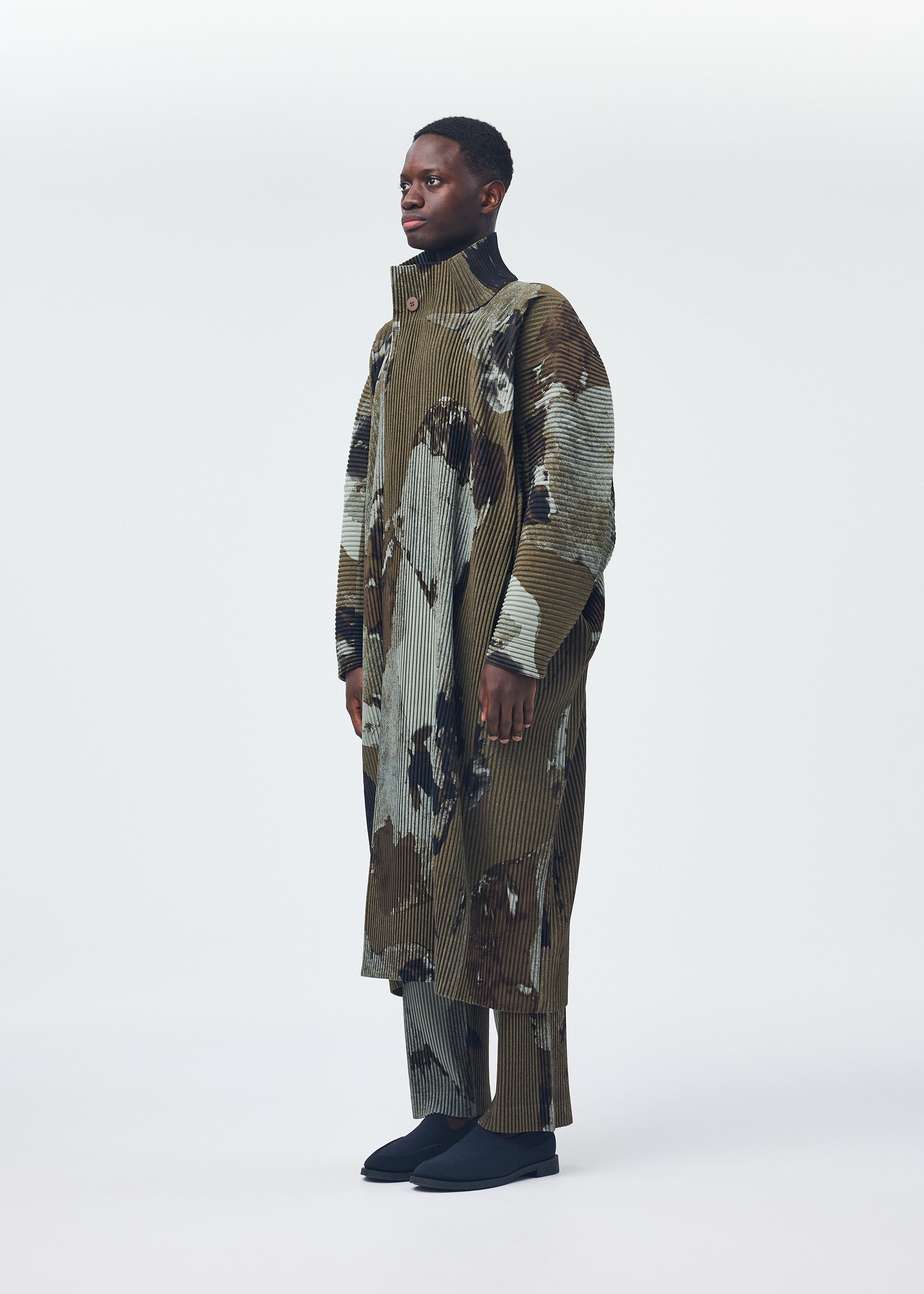 A model wears the Homme Plisse Issey Miyake PAINTED STONE coat.