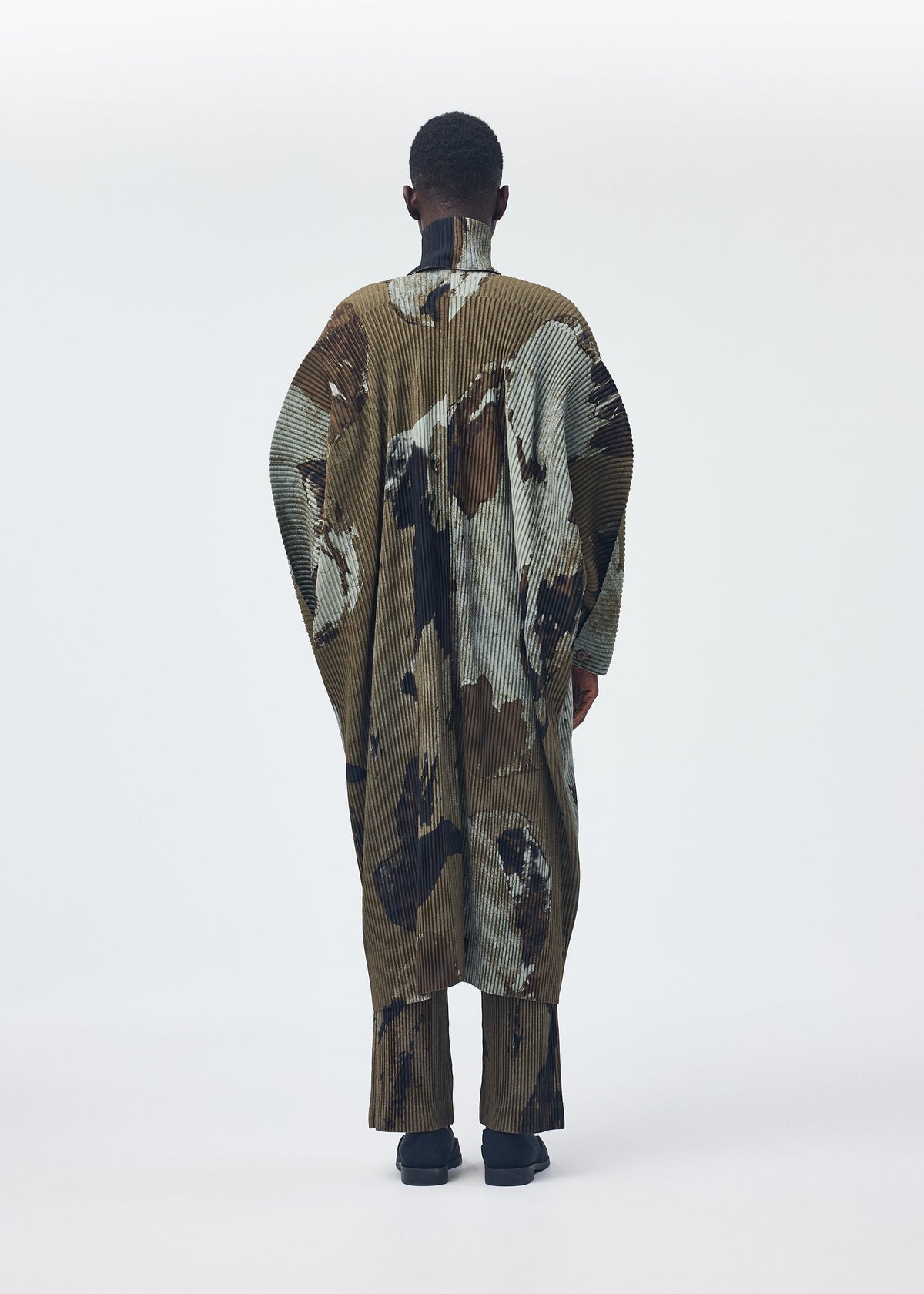 A model wears the Homme Plisse Issey Miyake PAINTED STONE coat.