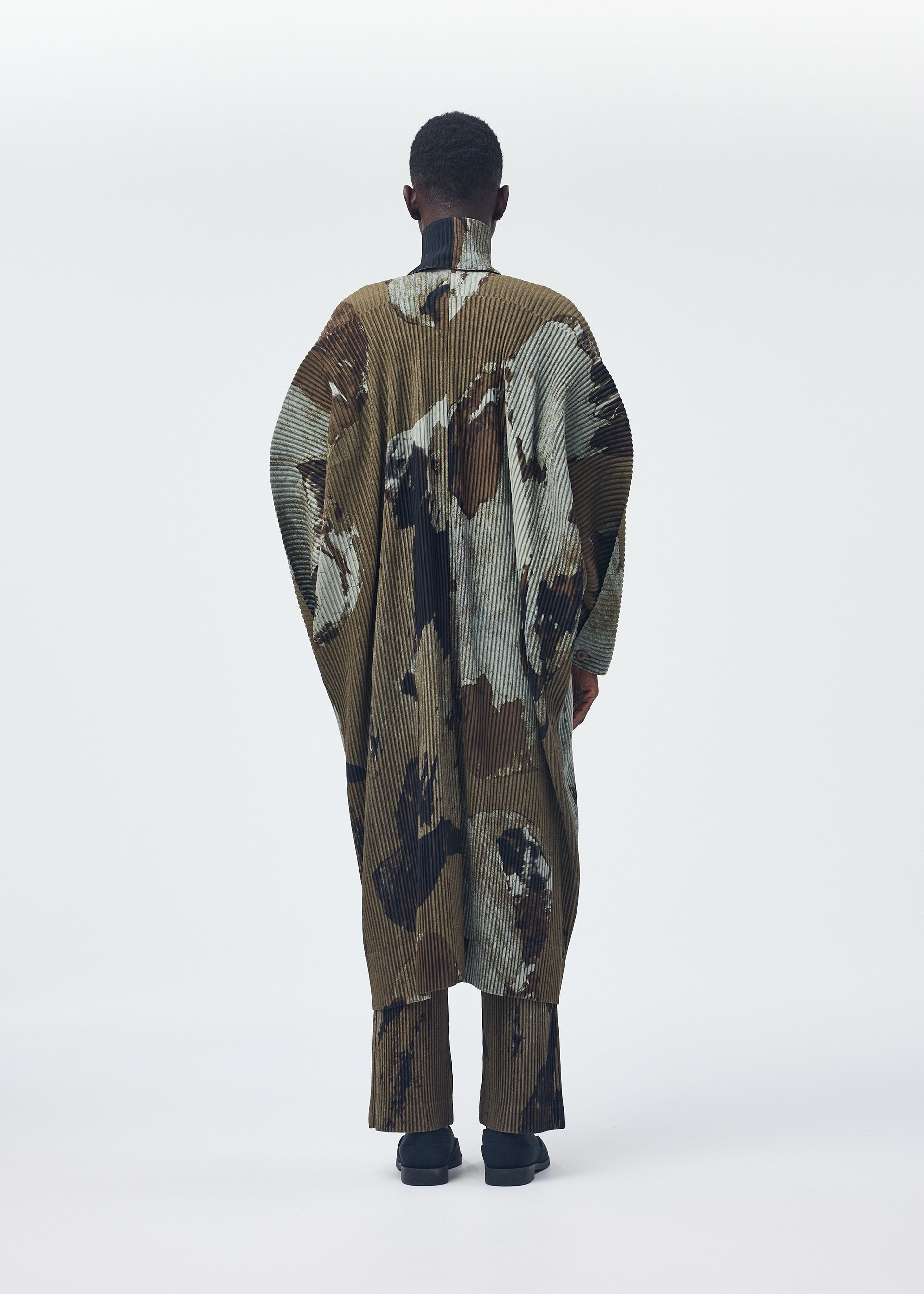 A model wears the Homme Plisse Issey Miyake PAINTED STONE coat.