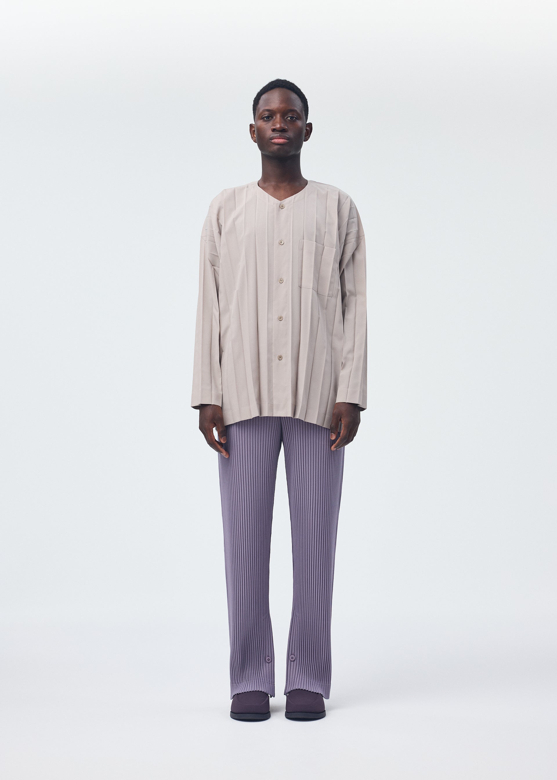A model wears the HOMME PLISSÉ ISSEY MIYAKE PLEATS BOTTOMS 1 trousers.