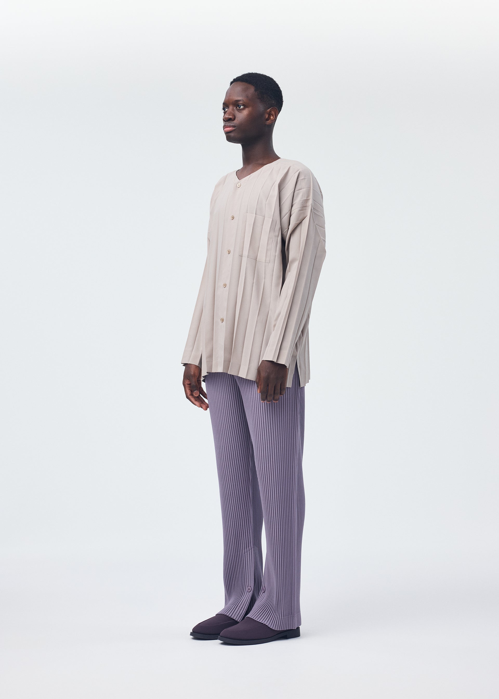 A model wears the HOMME PLISSÉ ISSEY MIYAKE PLEATS BOTTOMS 1 trousers.