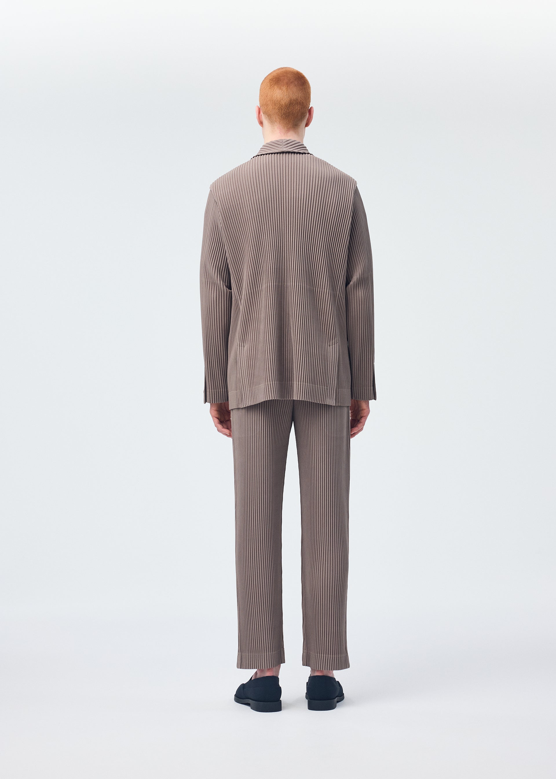 A model wears the Homme Plisse Issey Miyake TAILORED PLEATS 1 trousers.