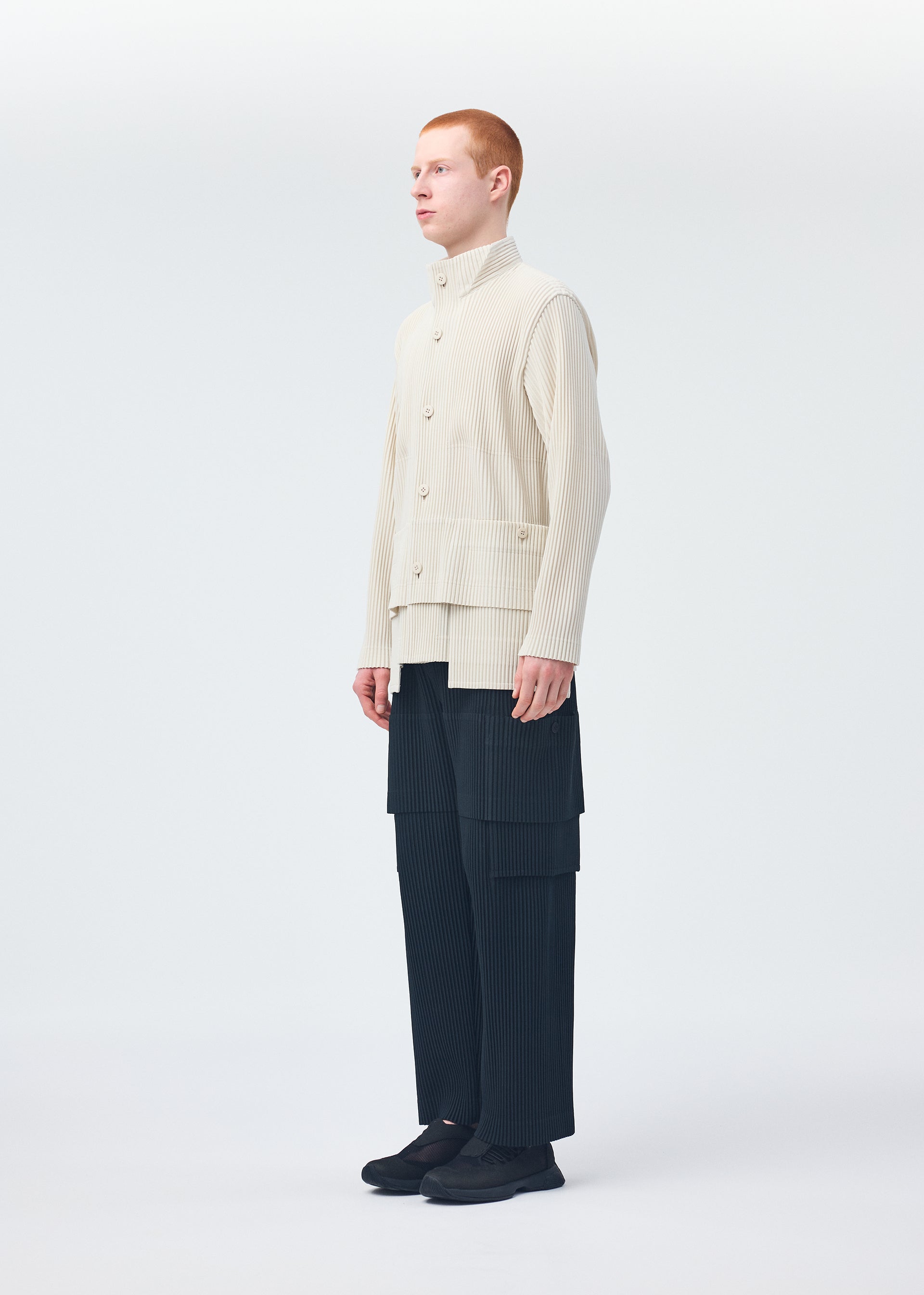 A model wears the HOMME PLISSÉ ISSEY MIYAKE MULTI POCKET trousers.