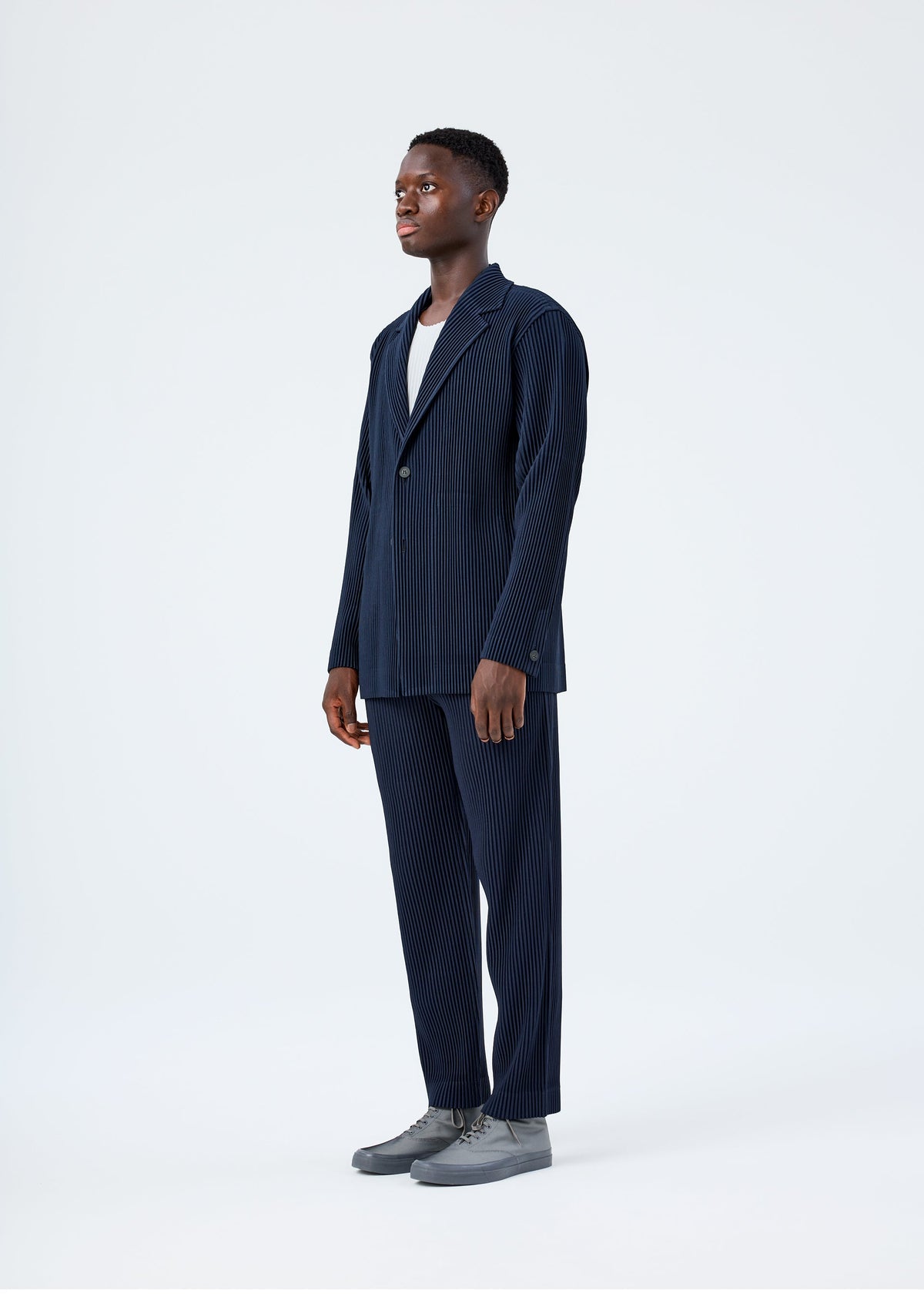 A model wears the HOMME PLISSÉ ISSEY MIYAKE BASICS basics-jacket-light-grey-fw26.