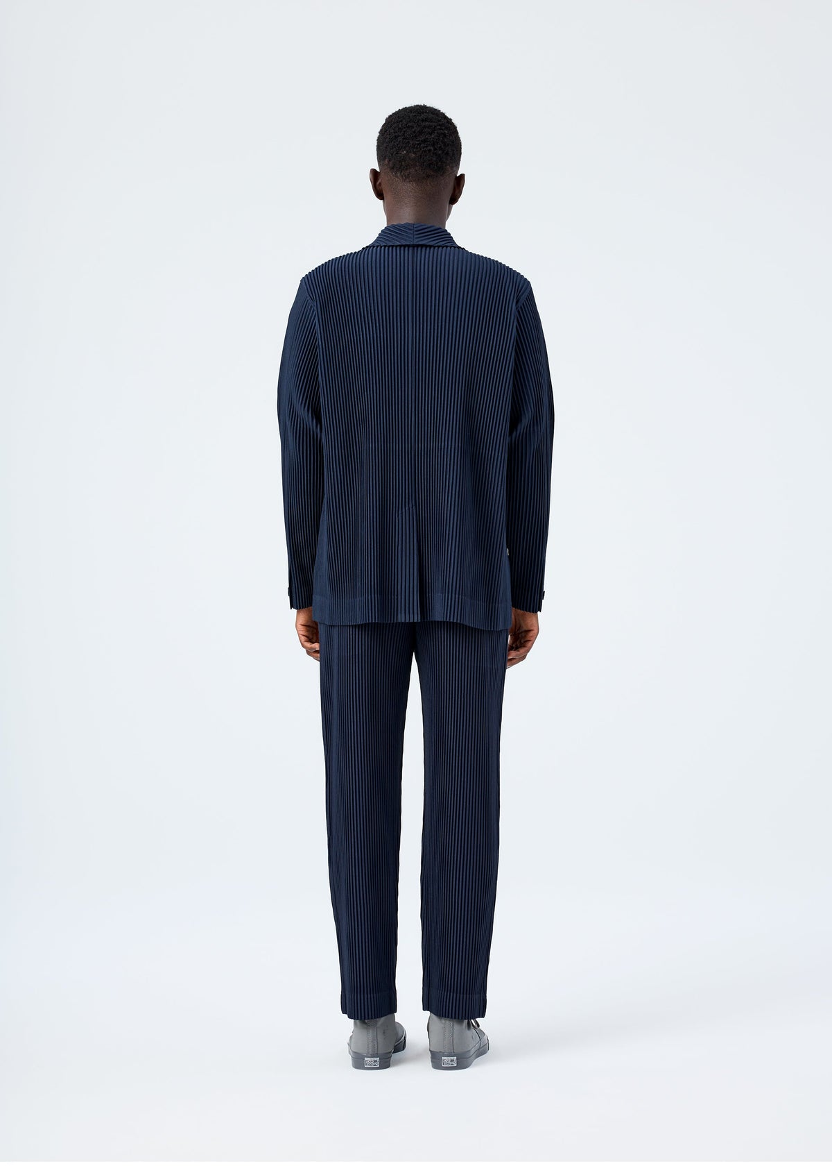 A model wears the HOMME PLISSÉ ISSEY MIYAKE BASICS basics-jacket-black-1-fw26.