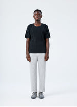 A model wears the HOMME PLISSÉ ISSEY MIYAKE BASICS basics-trousers-light-grey-fw26.