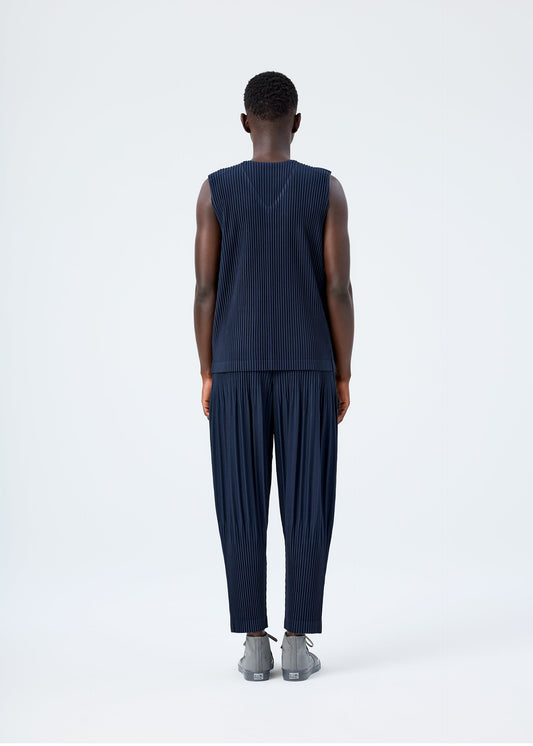 A model wears the HOMME PLISSÉ ISSEY MIYAKE BASICS basics-trousers-light-grey-3.