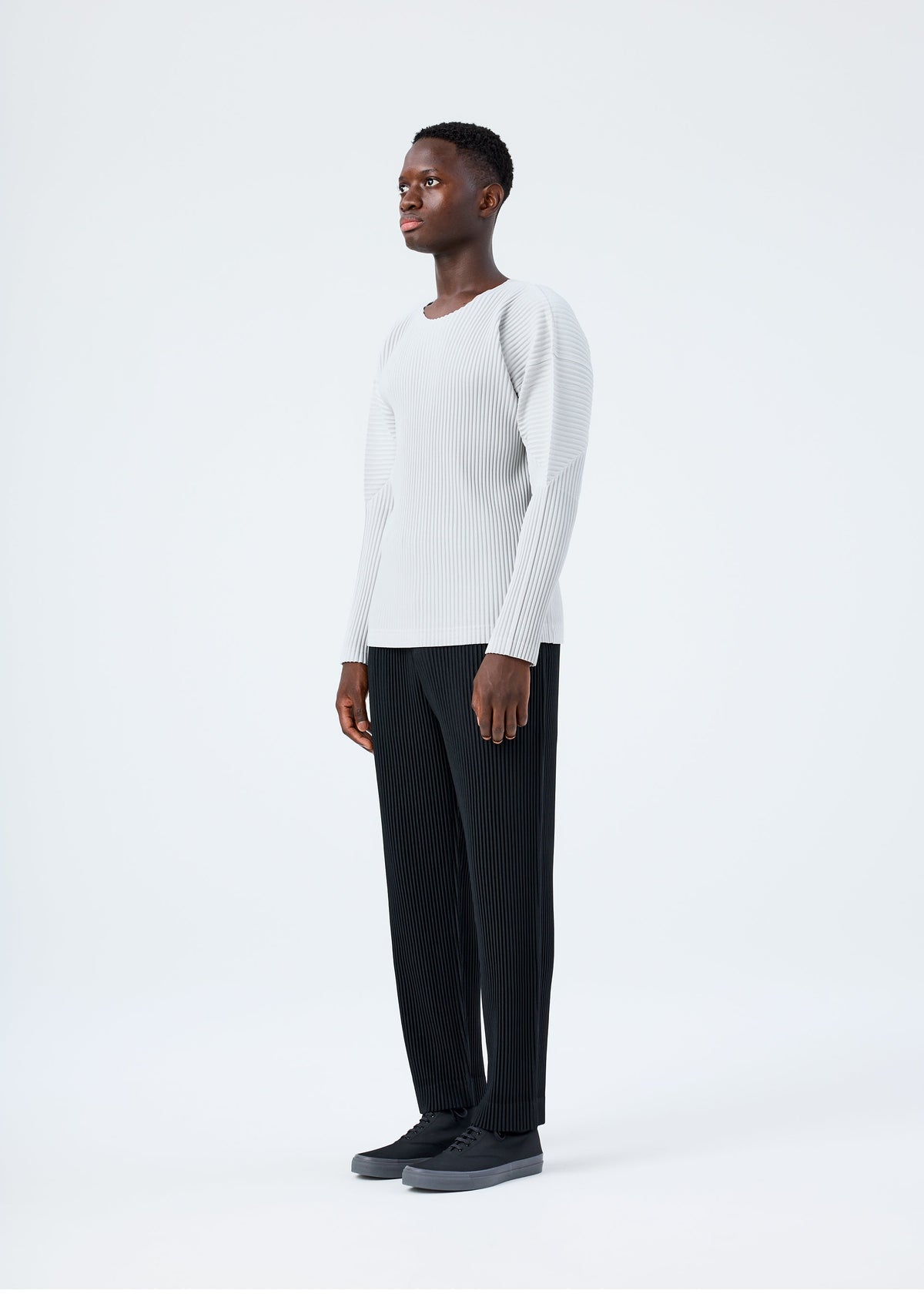 A model wears the HOMME PLISSÉ ISSEY MIYAKE BASICS basics-shirt-black-fw26.