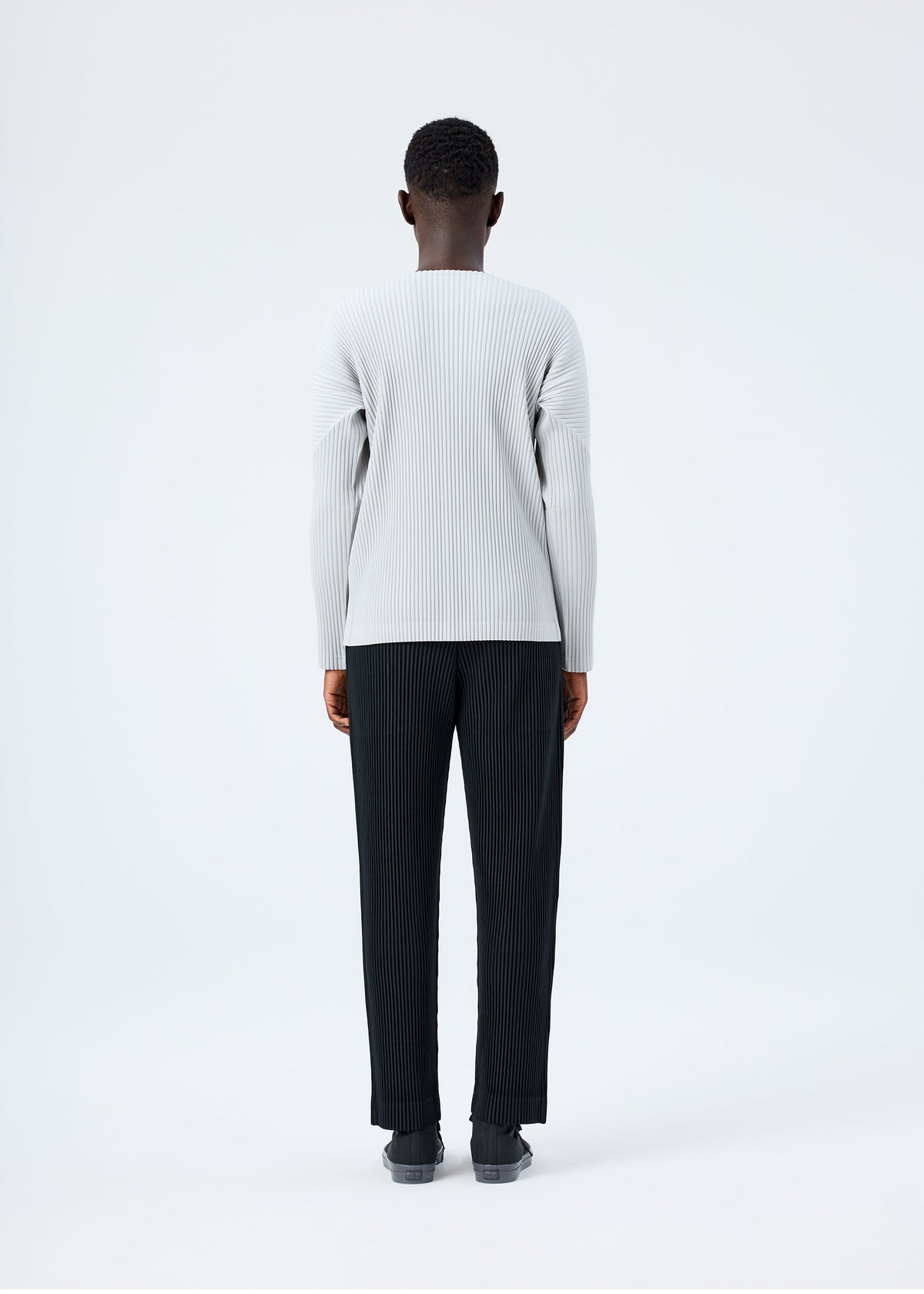 A model wears the HOMME PLISSÉ ISSEY MIYAKE BASICS basics-shirt-black-fw26.