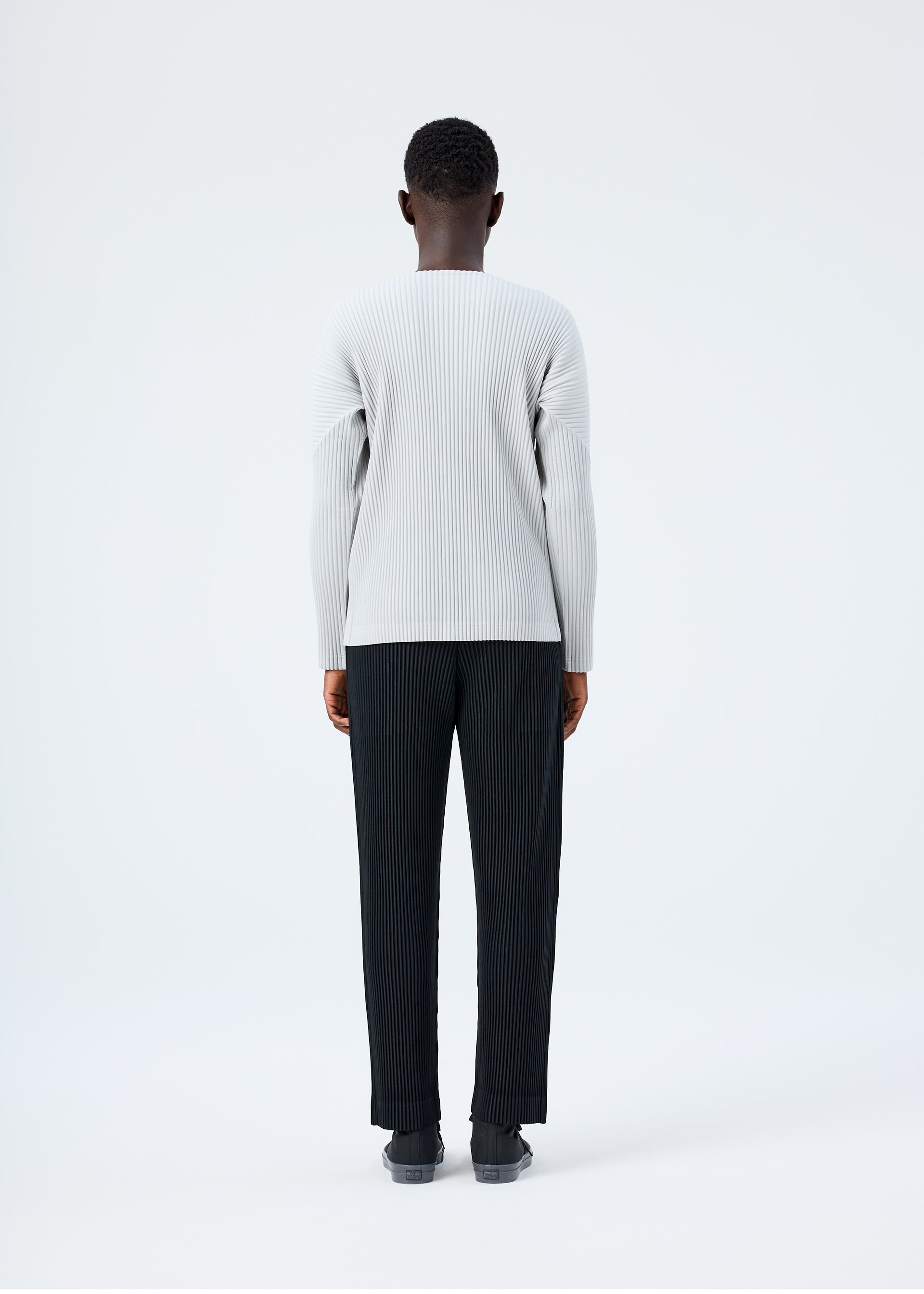 A model wears the HOMME PLISSÉ ISSEY MIYAKE BASICS basics-shirt-black-fw26.
