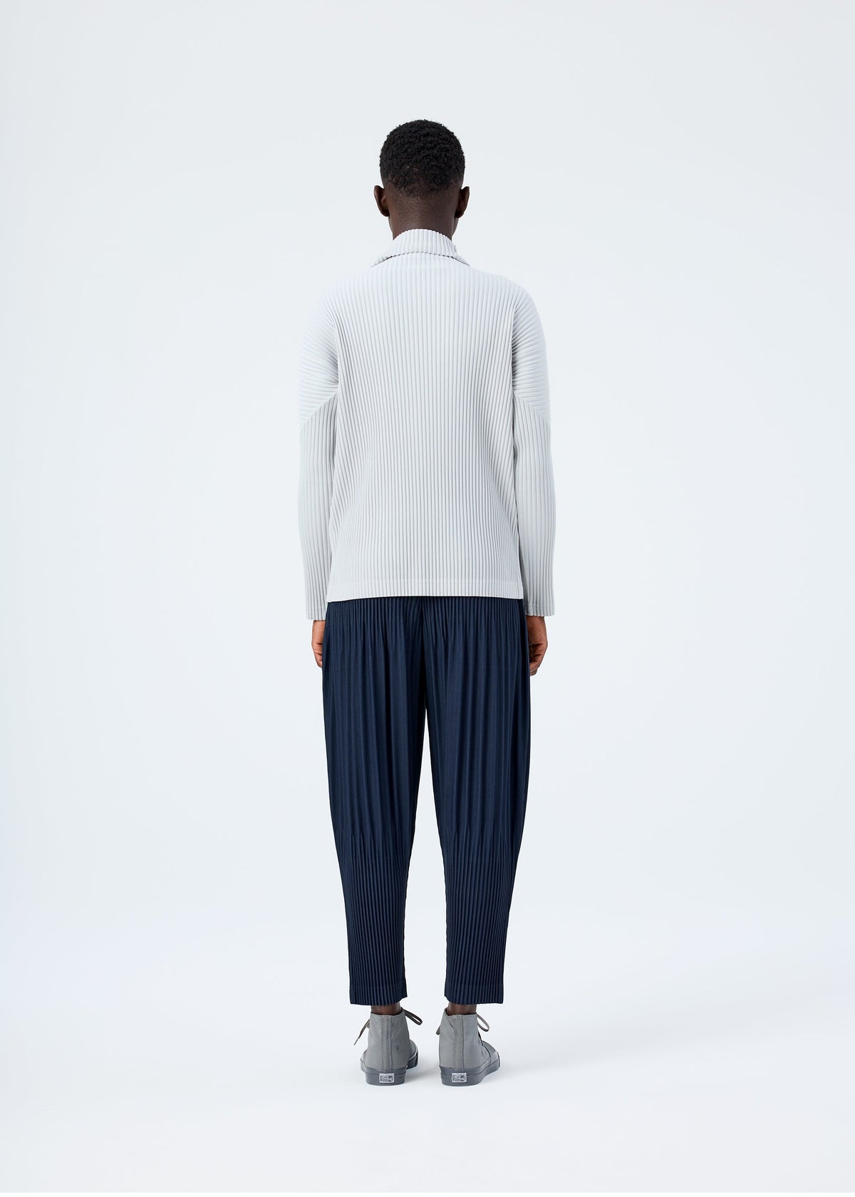 A model wears the HOMME PLISSÉ ISSEY MIYAKE BASICS basics-shirt-black-2-fw26.