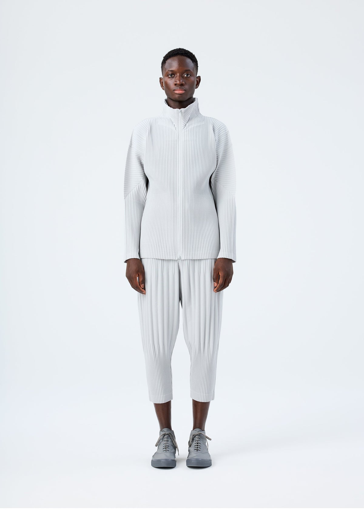 A model wears the HOMME PLISSÉ ISSEY MIYAKE BASICS basics-zipup-cardigan-light-grey.