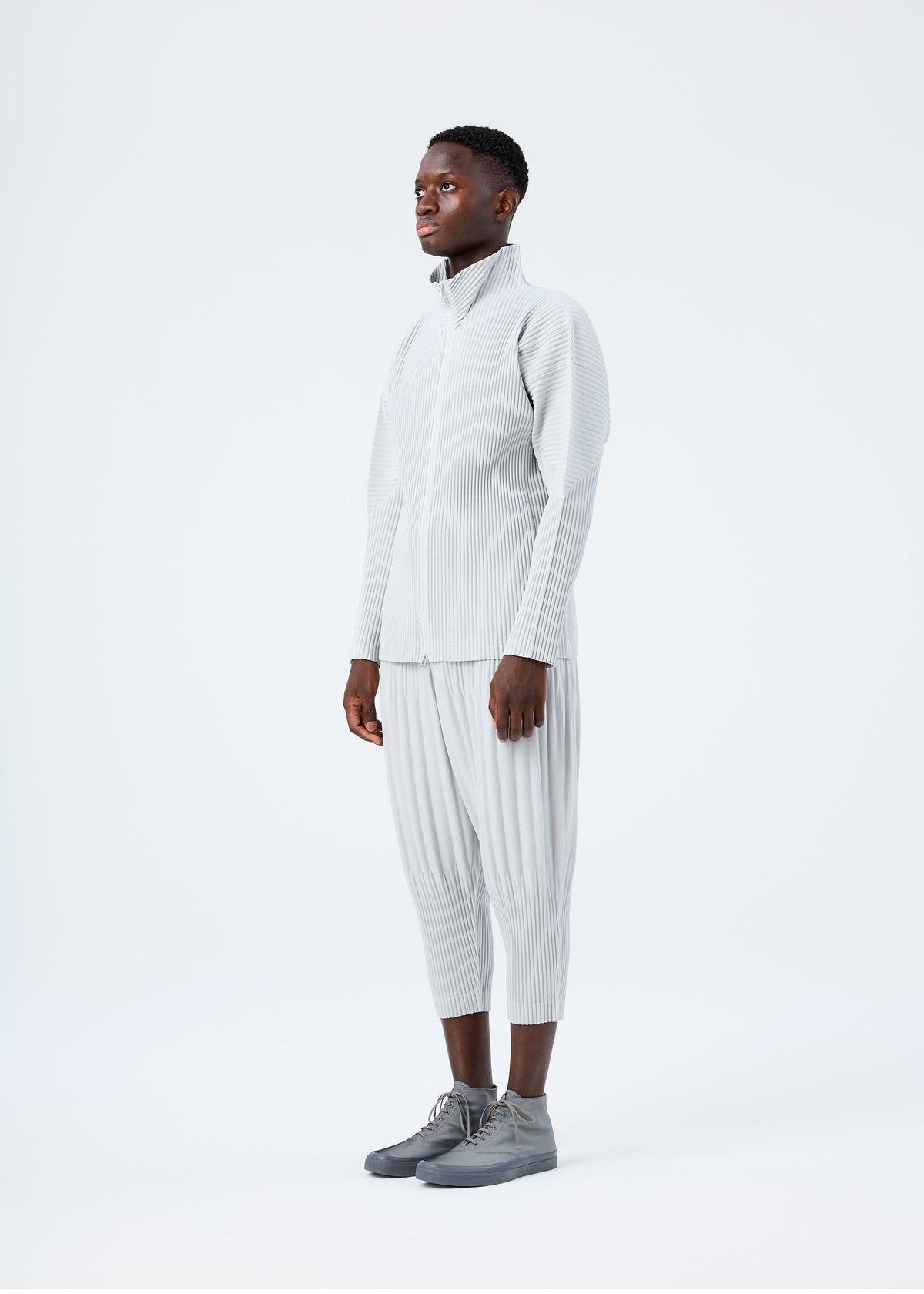 A model wears the HOMME PLISSÉ ISSEY MIYAKE BASICS basics-zipup-cardigan-navy-2.