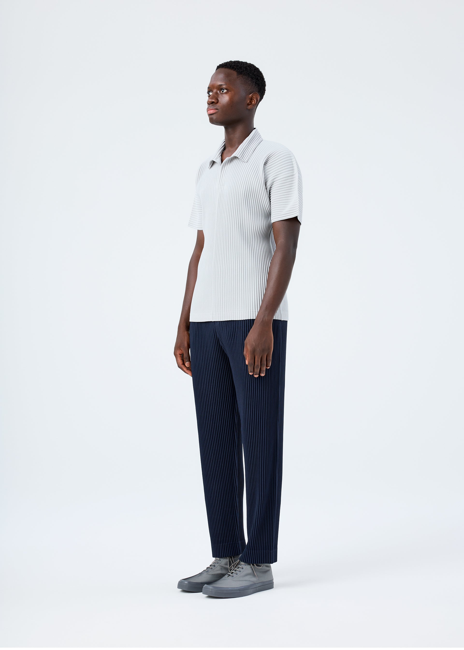 A model wears the HOMME PLISSÉ ISSEY MIYAKE BASICS basics-polo-shirt-black-fw26.