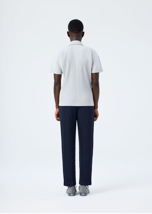 A model wears the HOMME PLISSÉ ISSEY MIYAKE BASICS basics-polo-shirt-navy-1.