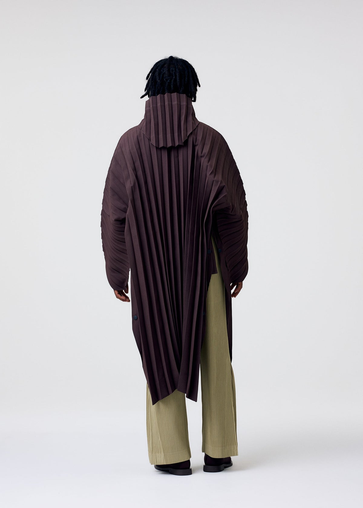 A model wears the HOMME PLISSE ISSEY MIYAKE EDGE COAT LIGHT prêt à porter.