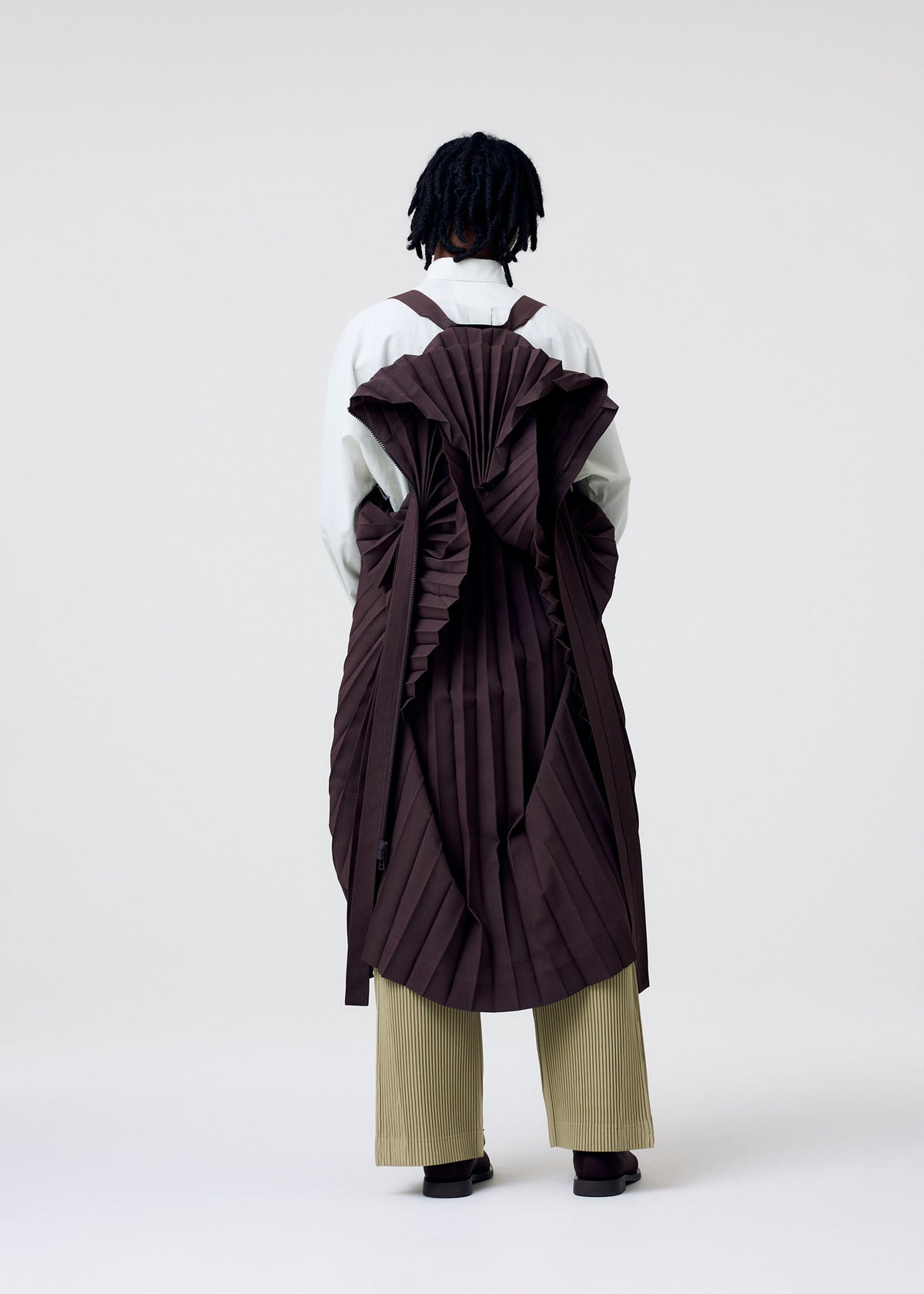 A model wears the HOMME PLISSE ISSEY MIYAKE EDGE COAT LIGHT prêt à porter.