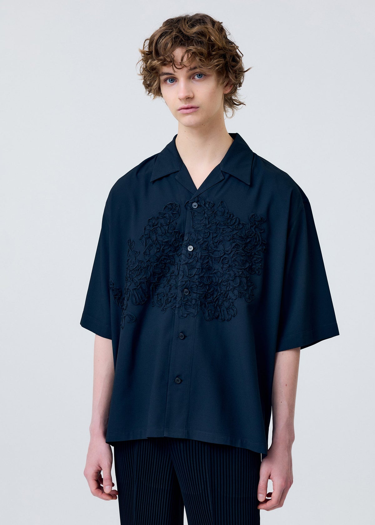 A model wears the Homme Plisse Issey Miyake EMBROIDERY PRESS SHIRT prêt à porter.