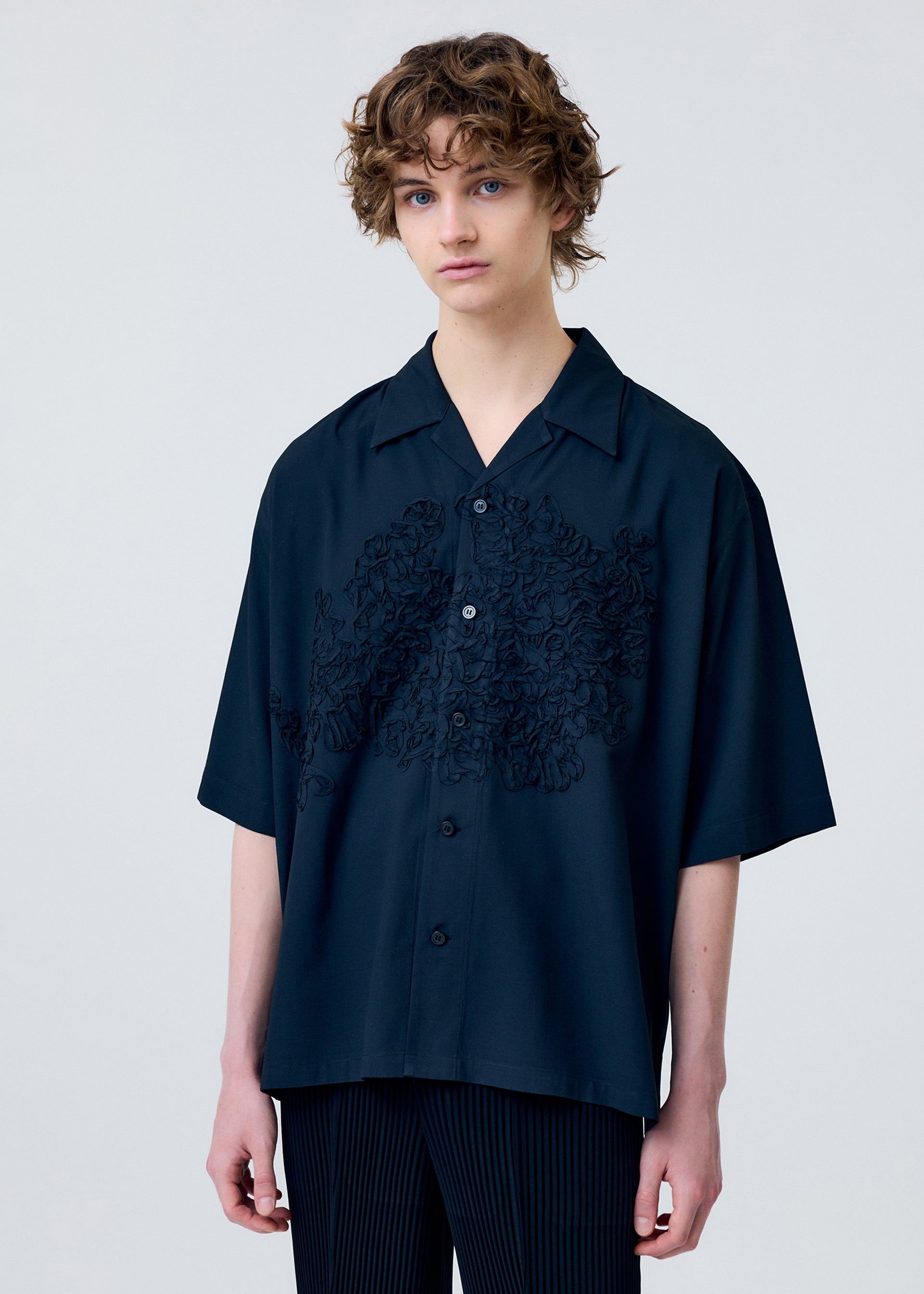 A model wears the Homme Plisse Issey Miyake EMBROIDERY PRESS SHIRT prêt à porter.
