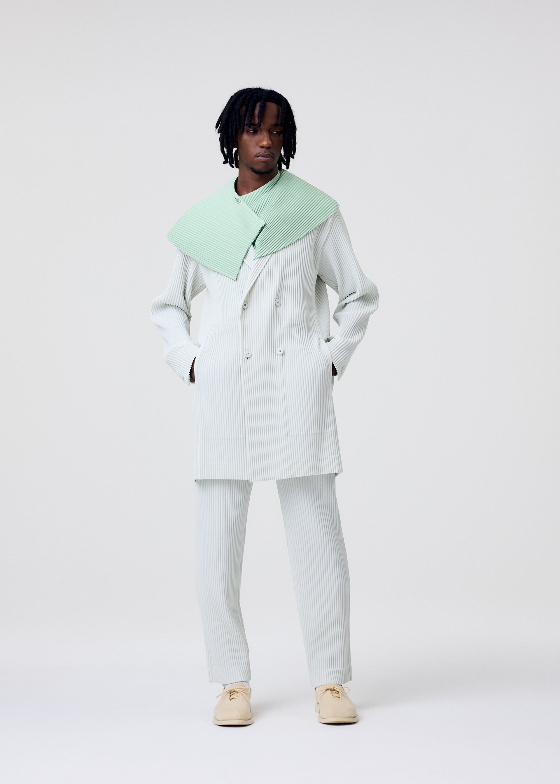 A model wears the HOMME PLISSÉ ISSEY MIYAKE TAILORED PLEATS 3 tailored-pleats-3-jacket-genova-metal-ochre-1.