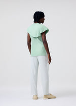 A model wears the HOMME PLISSÉ ISSEY MIYAKE TAILORED PLEATS 3 tailored-pleats-3-trousers-genova-metal-ochre.