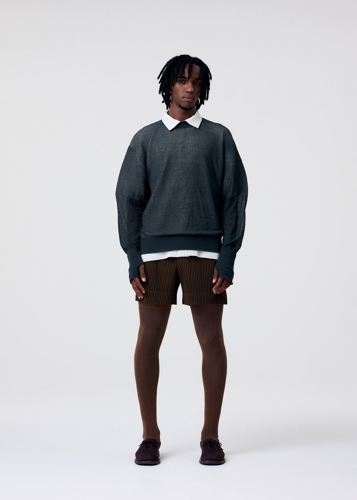A model wears the HOMME PLISSÉ ISSEY MIYAKE TAILORED PLEATS 3 tailored-pleats-3-trousers-black.